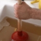 Plumber inspecting a clogged household drain to identify buildup, debris, and plumbing issues causing recurring drain clogs in the home | Causes of Recurring Drain Clogs in Your Home